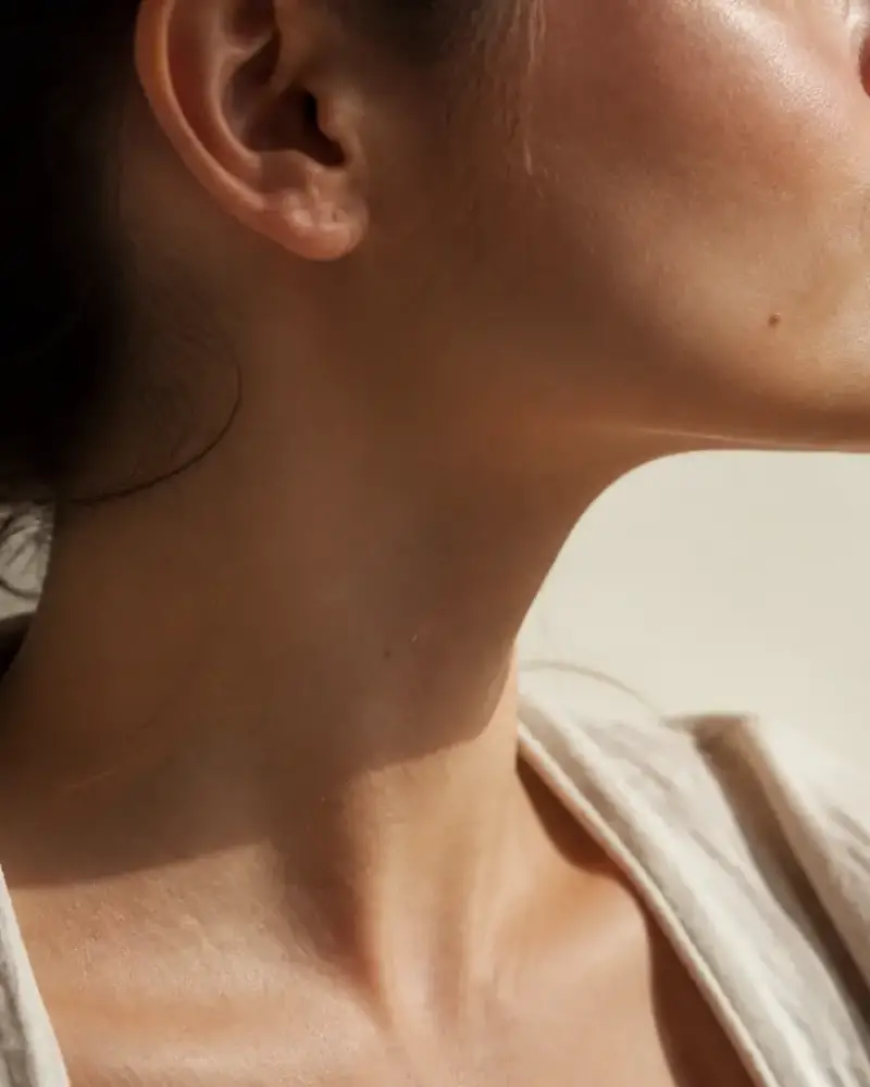 Profil d’un visage, ligne de la mâchoire et de l’oreille, peau mate, lumière rasante de fenêtre
