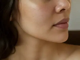 Joues et lèvre supérieure d’un visage de trois quarts, légères taches brunes diffuses, lumière douce de fenêtre